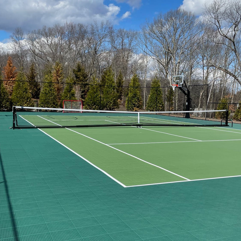 Representative photo: a portable tennis net system with regulation net on a freestanding base, shown on a green court